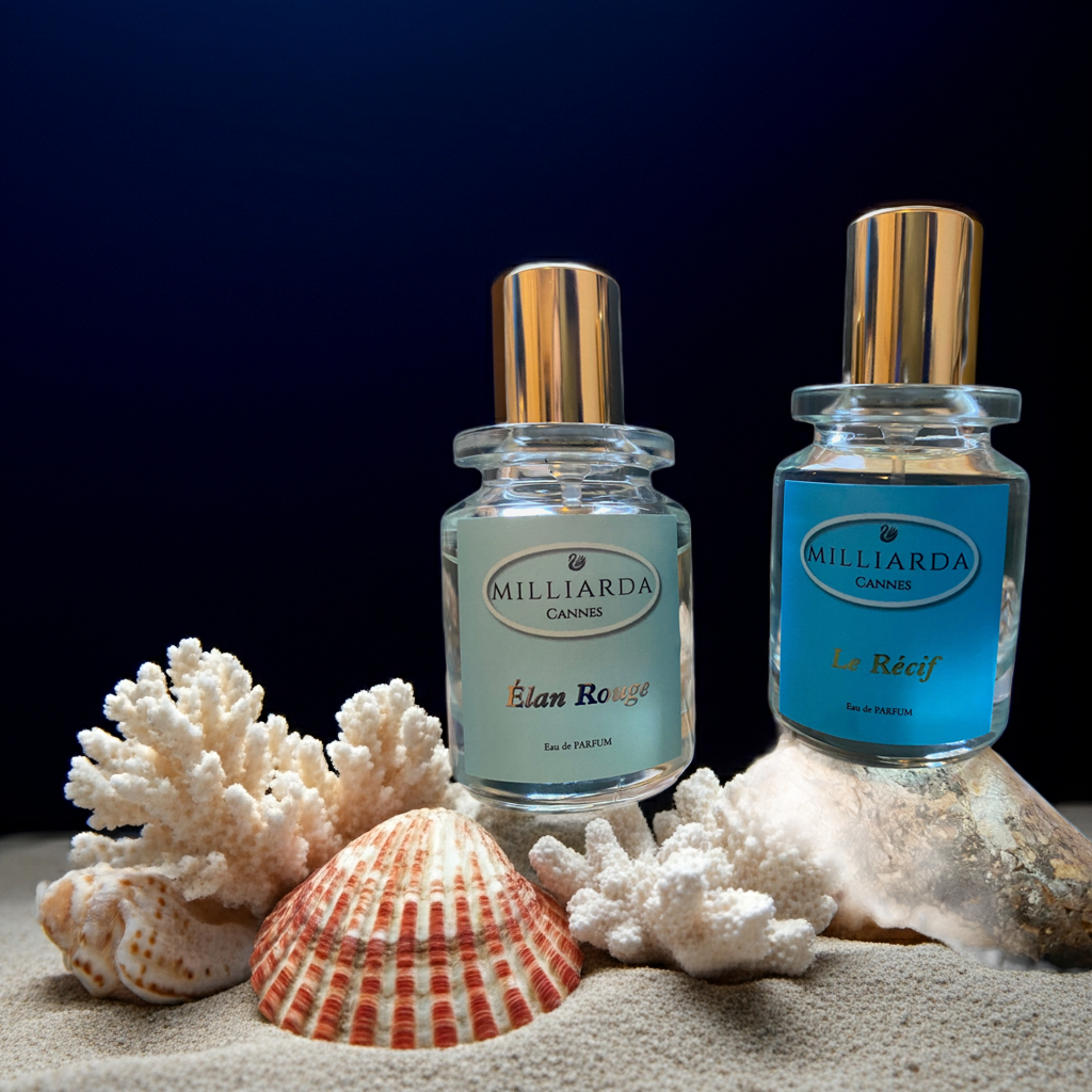Two 30 ml perfume bottles, Élan Rouge and Le Récif by Milliarda Cannes, displayed on sand with coral and seashells, inspired by the Mediterranean sea.